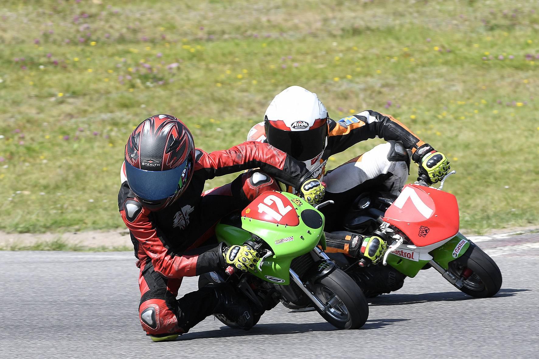 Två förare kör tätt intill varandra i en kurva på varsin minimoto