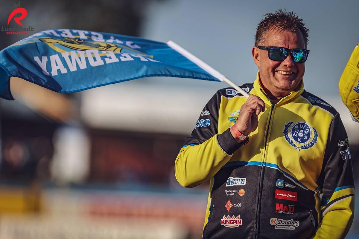 En glad funktionär håller upp en flagga för laget och skrattar